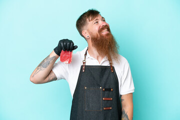 Wall Mural - Butcher man wearing an apron and serving fresh cut meat isolated on blue background thinking an idea while looking up