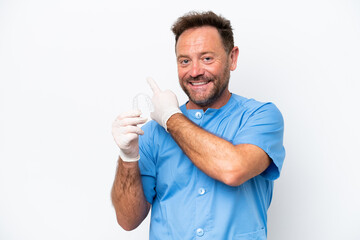 Wall Mural - Middle age dentist man holding envisaging isolated on white background pointing back