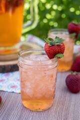 Canvas Print - Vertical closeup shot of the glass of strawberry lemonade with ice, decorated by strawberry