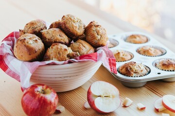 Poster - Closeup of the muffins in a white bowl and a form, with apples on a wooden table