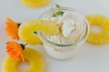 Canvas Print - Top view of a glass of ice cream surrounded by sliced pineapples and an orange flower