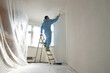 © nuclear_lily - Man stands on the stairs and paints the wall with a roller