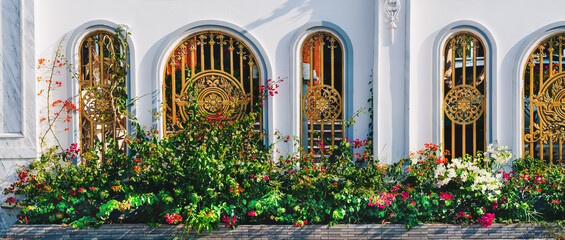 a white building with gold gate red yellow flowers background green luxury splendor