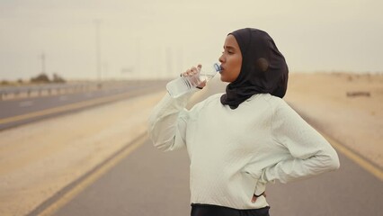 Wall Mural - Beautiful female runner wearing sport abaya running in the desert in dubai, united arab emirates. Concept about sport, and muslim culture