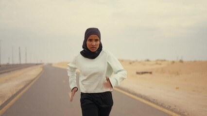 Wall Mural - Beautiful female runner wearing sport abaya running in the desert in dubai, united arab emirates. Concept about sport, and muslim culture