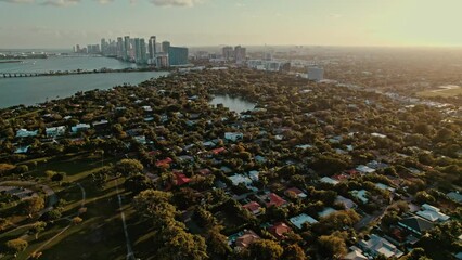 Sticker - Aerial view of a city with green vegetation at the shore at calm sunset