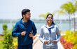 © WESTOCK - Happy Young couple jogging in park while talking each other during morning - concept of fitness, wellbeing and healthy lifestyle