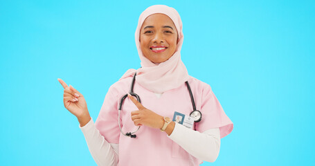 Canvas Print - Woman doctor pointing to mockup isolated on blue background for healthcare presentation or product placement space. Happy face of nurse or medical muslim person show advertising mock up in studio