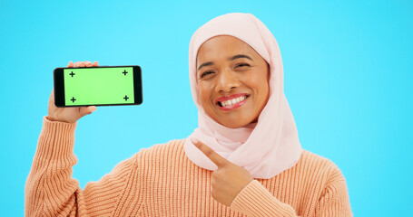 Canvas Print - Islam, phone or green screen and a woman on a blue background in studio holding a display with tracking markers. Muslim, mobile contact and an attractive young female showing a screen for marketing