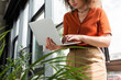 © LIGHTFIELD STUDIOS - cropped view of young businesswoman using laptop next to green plants in modern office.