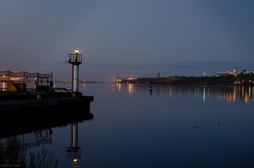 Seaport in a provincial town. Night. Port lights are reflected in the water.