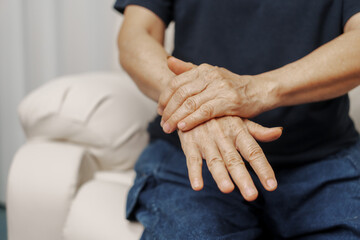 Close up hands of asian senior elderly woman with parkinson's disease symptom, hand numbness, finger lock, hand pain. Mental health and elderly care concept