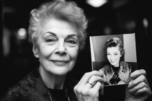 Senior Caucasian Woman Actress Holding Up A Photo Of Herself When She Was Younger Age. 