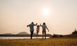 © Kiattisak - Happy Family enjoying a peaceful walk and running in a scenic field with a serene lake in the background.