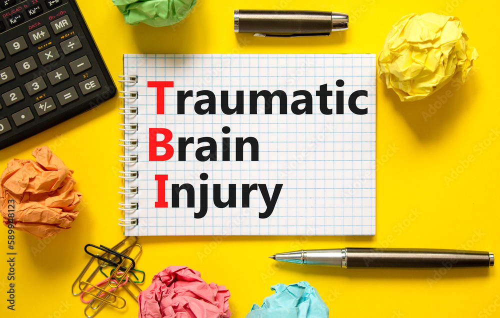 TBI traumatic brain injury symbol. Concept words TBI traumatic brain injury on white note on a beautiful yellow background. Black pen. Medical and TBI traumatic brain injury concept. Copy space.