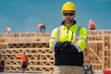 Wall Mural - Construction builder in building uniform on buildings construction background. Builder at the construction site. Man worker with helmet on construction site. Bilder in hardhat.