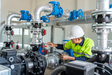 Asian Worker At Water Supply Stations Inspect And Maintain Condenser Equipment. Pumps In Power Substations For Supplying Clean Water In Industrial Estates. Industrial Plumbing.
