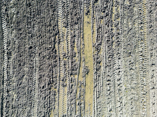 Top down drone view of a muddy farm field showing tyre tracks from a tractor.