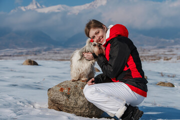 Poster - Young woman tourist with dog on winter mountains background