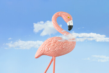 summer surreal colorful scene with pink flamingo among white clouds against pastel blue sky backgrou