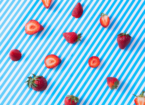 fresh strawberries on striped white and blue background. spring wallpaper. top view. minimal fruits 