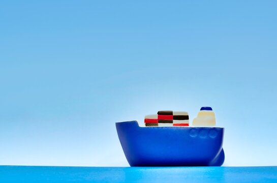 blue toy cargo ship sailing on calm seas with hazy sky in the background with copy space and shallow