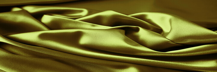 Wall Mural - Green yellow gold mustard silk satin cloth. Golden olive color.  Rich luxury elegant background for design. Soft folds on a shiny smooth fabric. Drapery. Light, glow, shimmer. Wide banner. Panoramic.