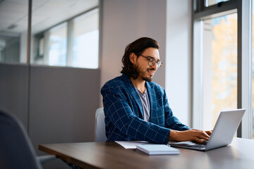 Happy businessman works on computer in office.