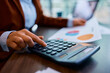 © Drazen - Close up of businesswoman using calculator while going through paperwork in office.