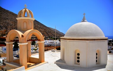 Vue sur un dôme blanc et un clocher avec en arrière plan la montagne et la ville de Emporio, Santorin, Grèce, Europe