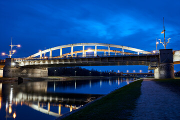 Poster - The steel structure of the road bridge over the Warta River during the night in the city of Poznan