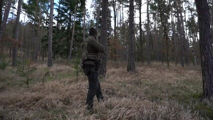 Wall Mural - Soldier during a military operation, fully equipped camouflage on a reconnaissance military mission, rifles in firing position. They run in formation through the dense forest. Ukraine war