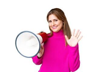 Canvas Print - Middle age woman over isolated background holding a megaphone and saluting with hand with happy expression