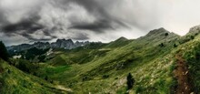 Scenic Landscape Of Mountains With Green Slopes Under A Cloudy Dark Sky