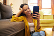 © Nina/peopleimages.com - Smile, relax and a woman with a phone for an app, communication and social media. Happy, funny and a girl reading a text message, chat or notification on a mobile in the living room of a house