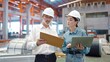© M Stocker - Two engineer manager leader and woman assistant holding laptop wearing helmet talking and checking production standing in workplace area at manufacturing factory