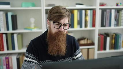 Canvas Print - Young redhead man student stressed using computer studying at library university