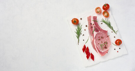 Wall Mural - Raw pork tenderloin on the bone and spices on a white background. Portion for lunch and dinner, top view