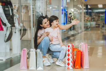 Wall Mural - young mother and daughter holding shopping bags, shopping in the mall. Family shopping.