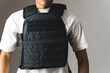 a muscular unknown man in a white T-shirt wearing a bulletproof vest on a grey background. High quality photo