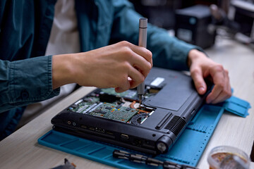 Wall Mural - Closeup of unrecognizable engineer technician hands repairing faulty on laptop computer in electric device technology service, male using special tools. Maintenance notebook support service engineer