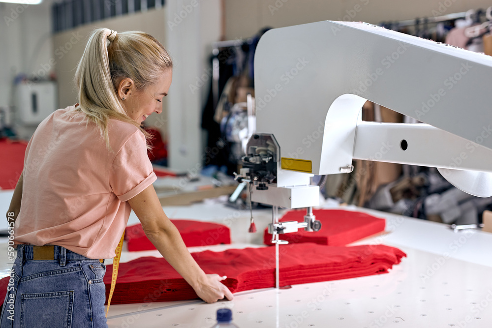 Working Clothes Machine Rear view on young caucasian blonde seamstress working on sewing ...