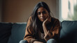 © bahadirbermekphoto - Unhappy depressed Indian woman holding head in hands, sitting alone on couch at home, stressed young female worried about bad relationship Generative AI
