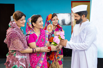 Indian man politician receive bouquet of flower by group of traditional women wearing sari. Concept of political leader welcome by people or society.