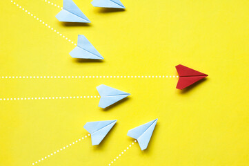 Wall Mural - Top view of white paper airplanes origami chasing red airplane on yellow background with customizable space for text or ideas. Leadership skills concept and copy space