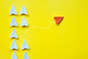 Wall Mural - Red paper airplane origami leaving other white airplanes on yellow background with customizable space for text or ideas. Leadership skills concept and copy space