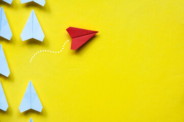 Wall Mural - Top view of red paper airplane origami leaving other white airplanes on yellow background with customizable space for text or ideas. Leadership skills concept and copy space