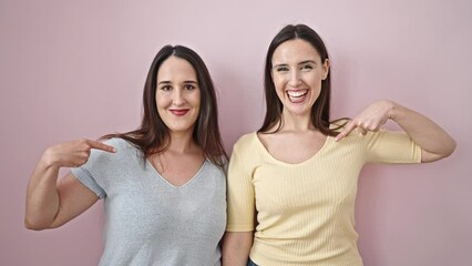 Poster - Two women smiling confident pointing with finger to herself over isolated pink background