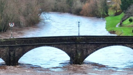 Canvas Print - Cars driving on the Usk bridge over the river with trees in the background