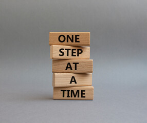 Wall Mural - One step at a time symbol. Concept words One step at a time on wooden blocks. Beautiful grey background. Business and One step at a time concept. Copy space.